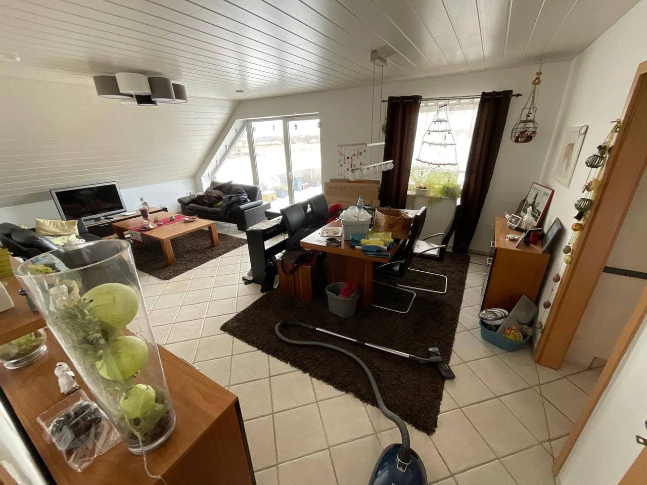 Eingerichtete Dachgeschosswohnung mit Esstisch und Sofa vor der Auflösung